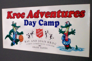 Kroc Adventures Day Camp Sign A colorful sign for "Kroc Adventures Day Camp" at the Ray and Joan Kroc Corps Community Center in Grand Rapids, featuring cartoon alligators and The Salvation Army logo.