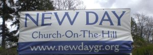 New Day Church-On-The-Hill Banner Banner displaying "NEW DAY Church-On-The-Hill" with the website URL "www.newdaygr.org," set against a backdrop of trees and a cloudy sky.