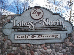Lakes of the North Entrance Sign An entrance sign for Lakes of the North, a residential and recreational community offering golf and dining, mounted on a stone wall with decorative lettering.