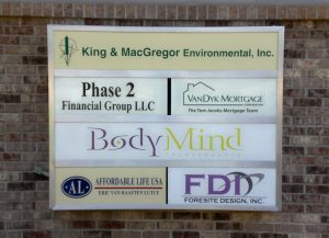 Business Directory Sign for Multiple Companies A business directory sign mounted on a brick wall, listing multiple companies including King & MacGregor Environmental, Phase 2 Financial Group, VanDyk Mortgage, Body Mind Incorporated, Affordable Life USA, and Foresite Design Inc.