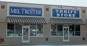 Mel Trotter Thrift Store Front The storefront of Mel Trotter Thrift Store featuring blue signage with white lettering, striped awnings, and large glass windows displaying store details.