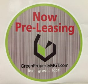 Green Property Management Pre-Leasing Sign A circular sign with a gray striped background, green border, and bold red text stating "Now Pre-Leasing," featuring the GreenPropertyMGT.com logo and tagline "live. green. local."