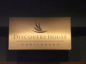 Discovery House Publishers Sign A brushed metal sign displaying the logo and name of Discovery House Publishers, featuring a stylized wave design above the text.